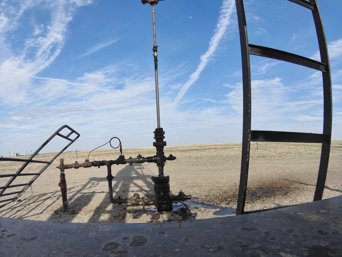 Oil visible around the wellhead and on the ground.